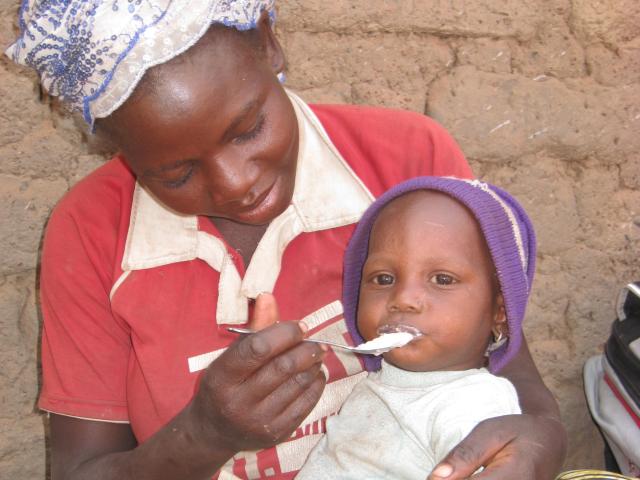 mother holding and feeding young child 